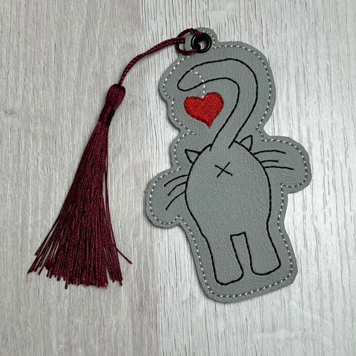 Vinyl bookmark of a grey cat butt with maroon tassel